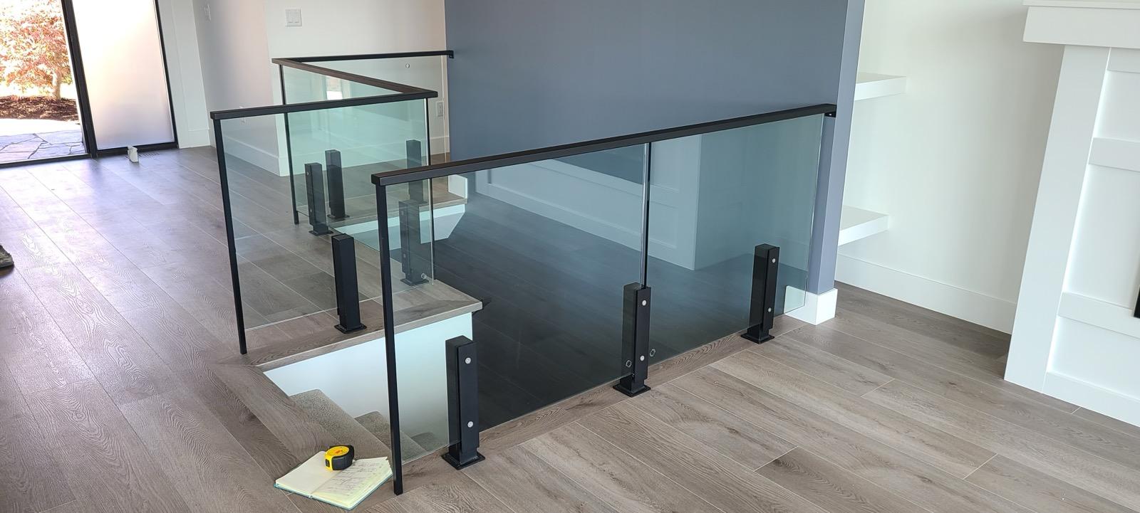 Interior glass railing system with black metal posts and handrail